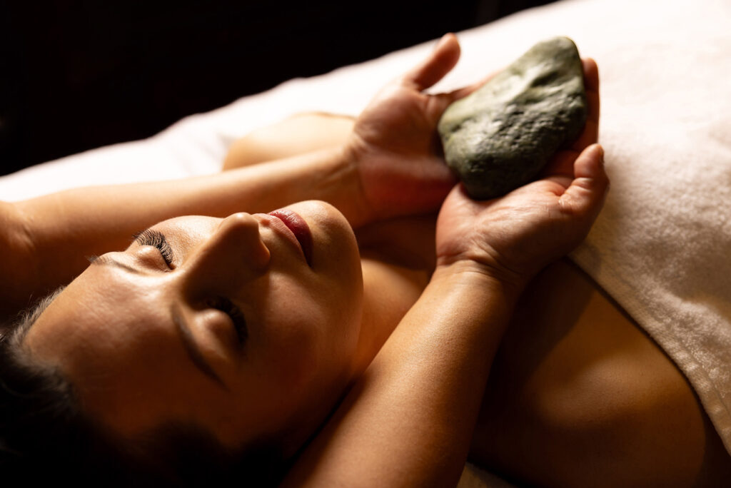 Therapist holding a mauri stone during a massage at Wai Ariki's Spa Sanctuary, a moment included in every session.