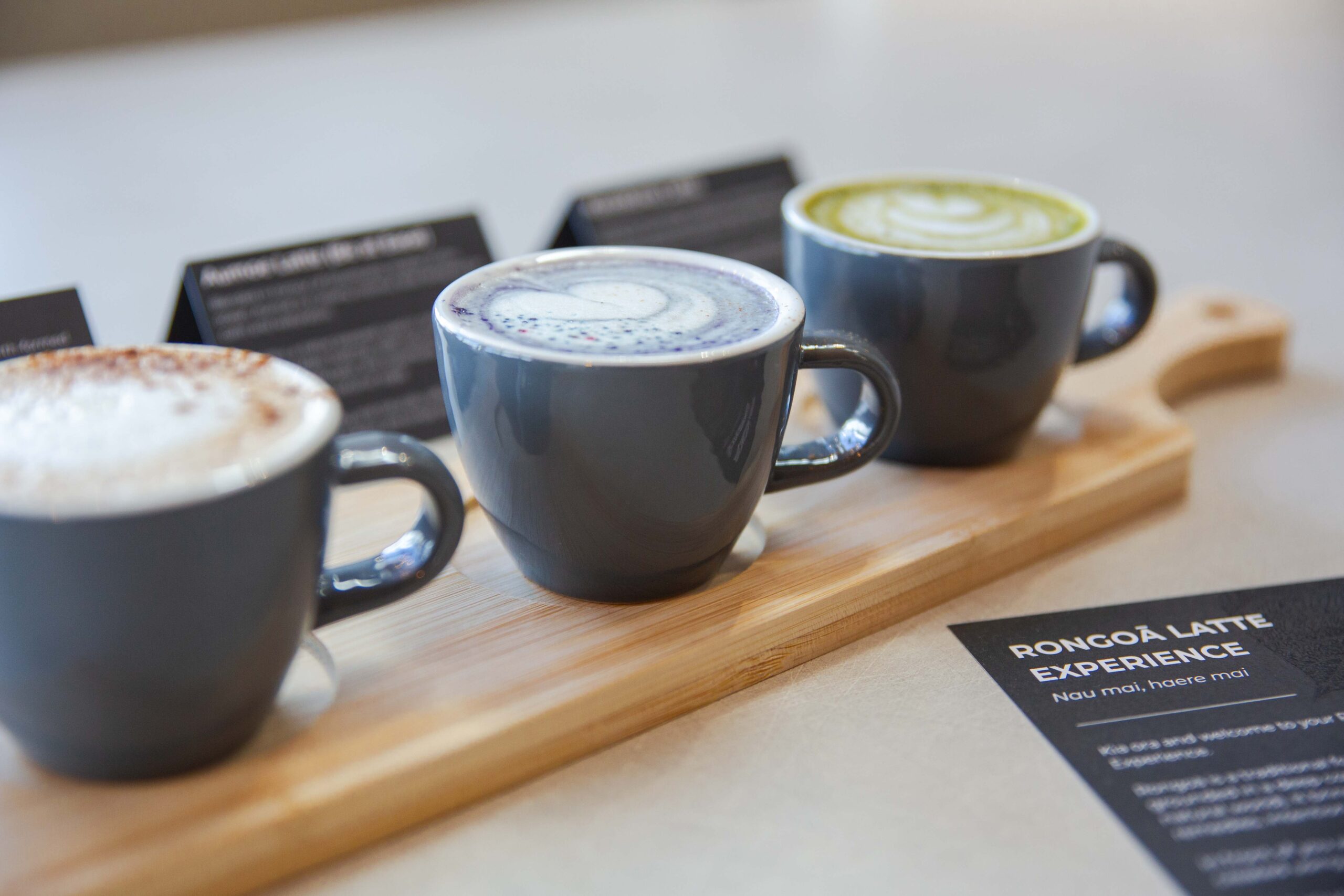 Three native botanical lattes presented on a wooden tasting tray at Te Rourou Café.