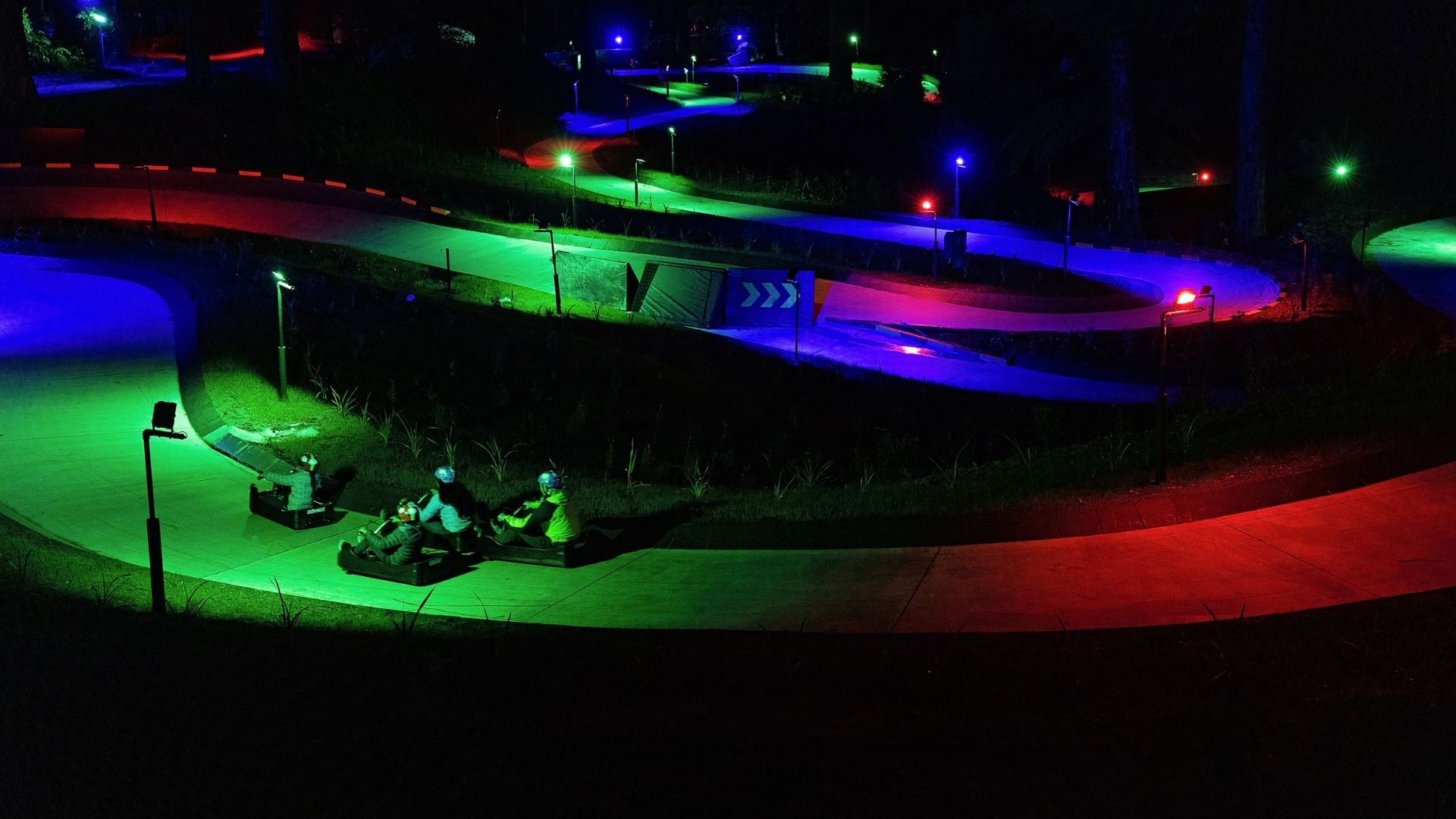 Twilight Luge track illuminated with colourful lights after dark at Skyline Rotorua.
