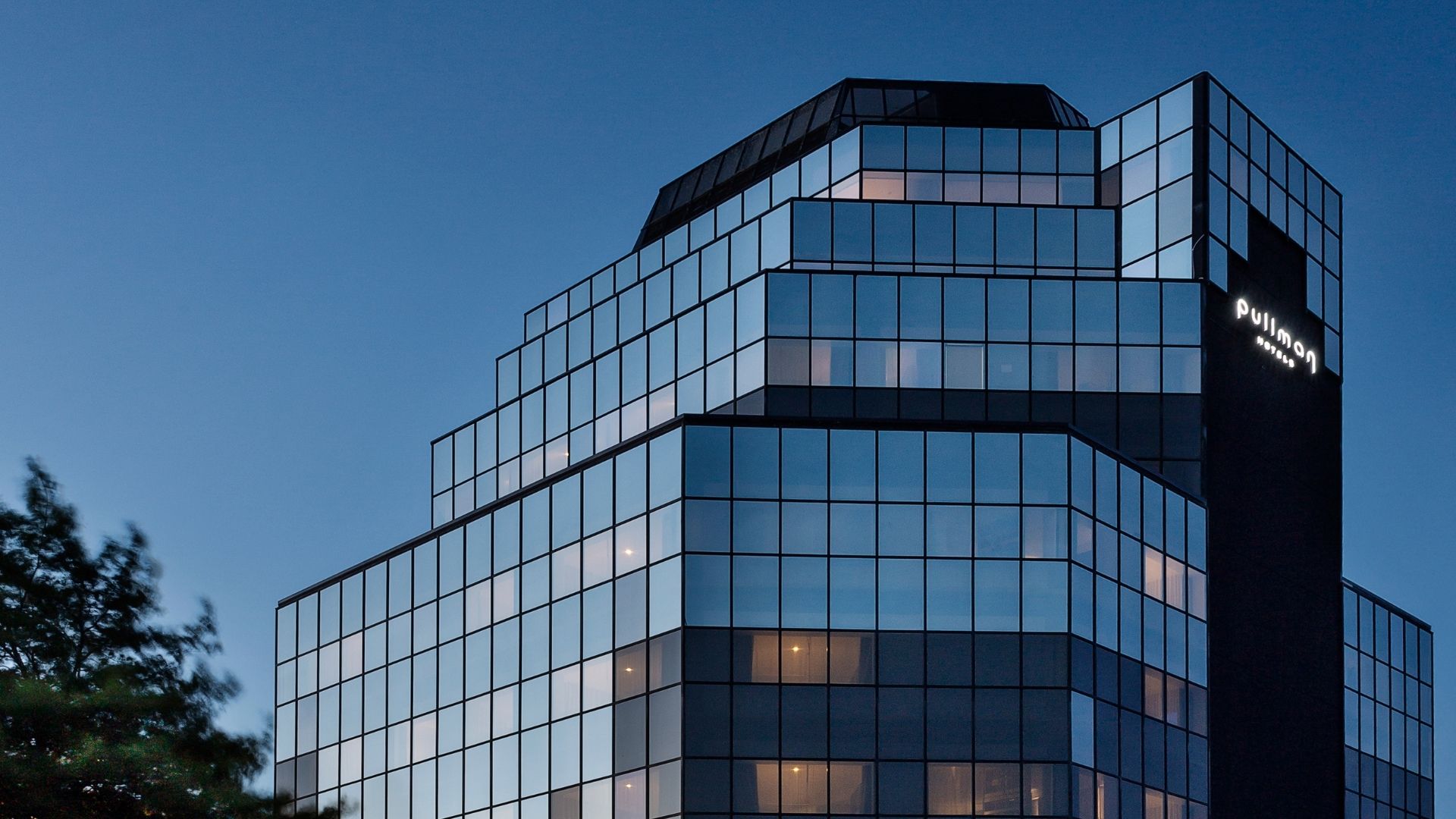 Exterior of Pullman Rotorua with its glass façade reflecting the evening light.
