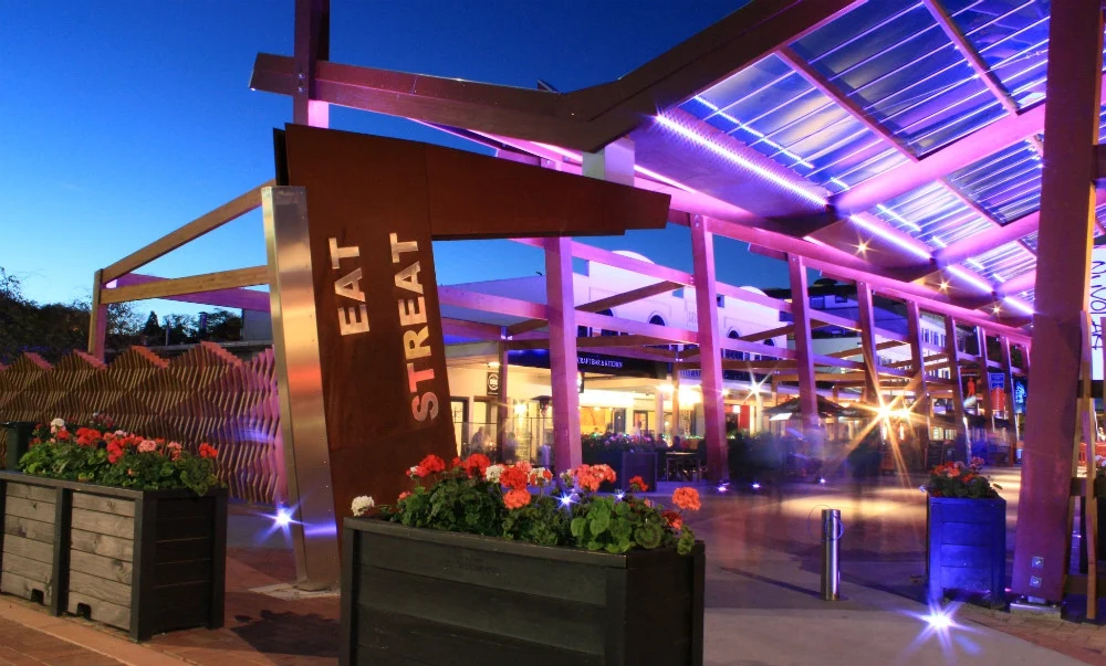 Eat Streat in central Rotorua illuminated with purple lights in the evening.